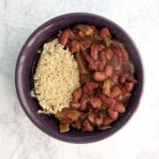 A bowl with slow cooker vegan red beans alongside cooked brown rice. Text overlay reads "Red Beans & Rice. Big Batch Leftovers. Easy As Cookies."