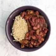 A bowl with slow cooker vegan red beans alongside cooked brown rice. Text overlay reads "Red Beans & Rice. Dump & Go Slow Cooker. Easy As Cookies."