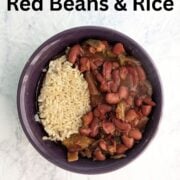 A bowl with slow cooker vegan red beans alongside cooked brown rice. Text overlay reads "Slow Cooker Red Beans & Rice. Vegan • Cajun Spiced. Easy As Cookies."