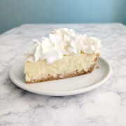 A slice of coconut cream pie with whipped cream on top.