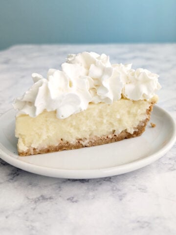 A slice of coconut cream pie with whipped cream on top.