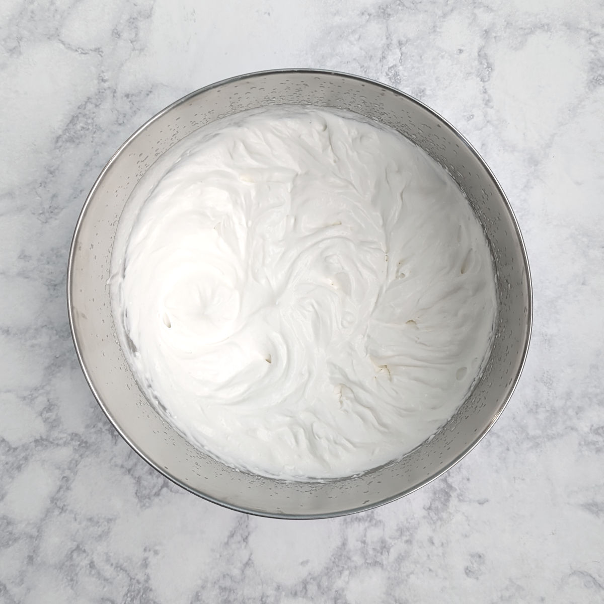 Heavy cream whipped to medium peaks, in a bowl.